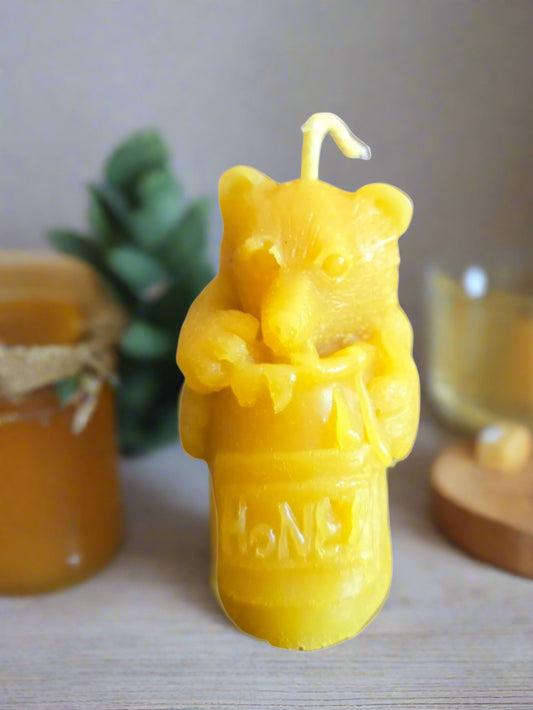 Beeswax candle shaped like a bear holding honey, with 'honey' text, on a neutral background.