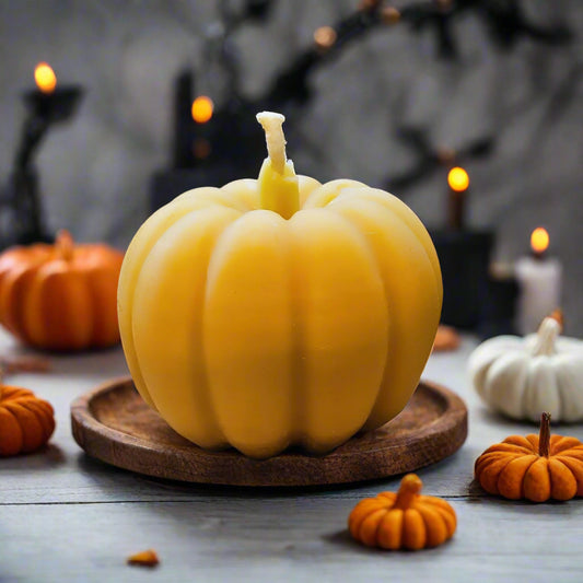 Yellow beeswax candle shaped like a pumpkin on a textured surface with a beige background