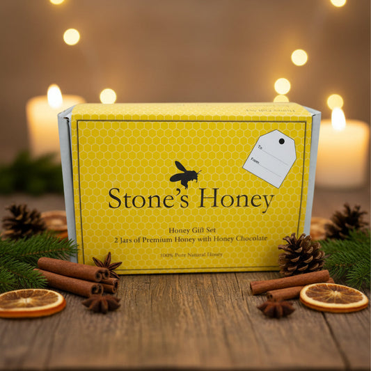 Yellow box with 'Stone's Honey' branding on a wooden table with candles and cinnamon sticks in the background.